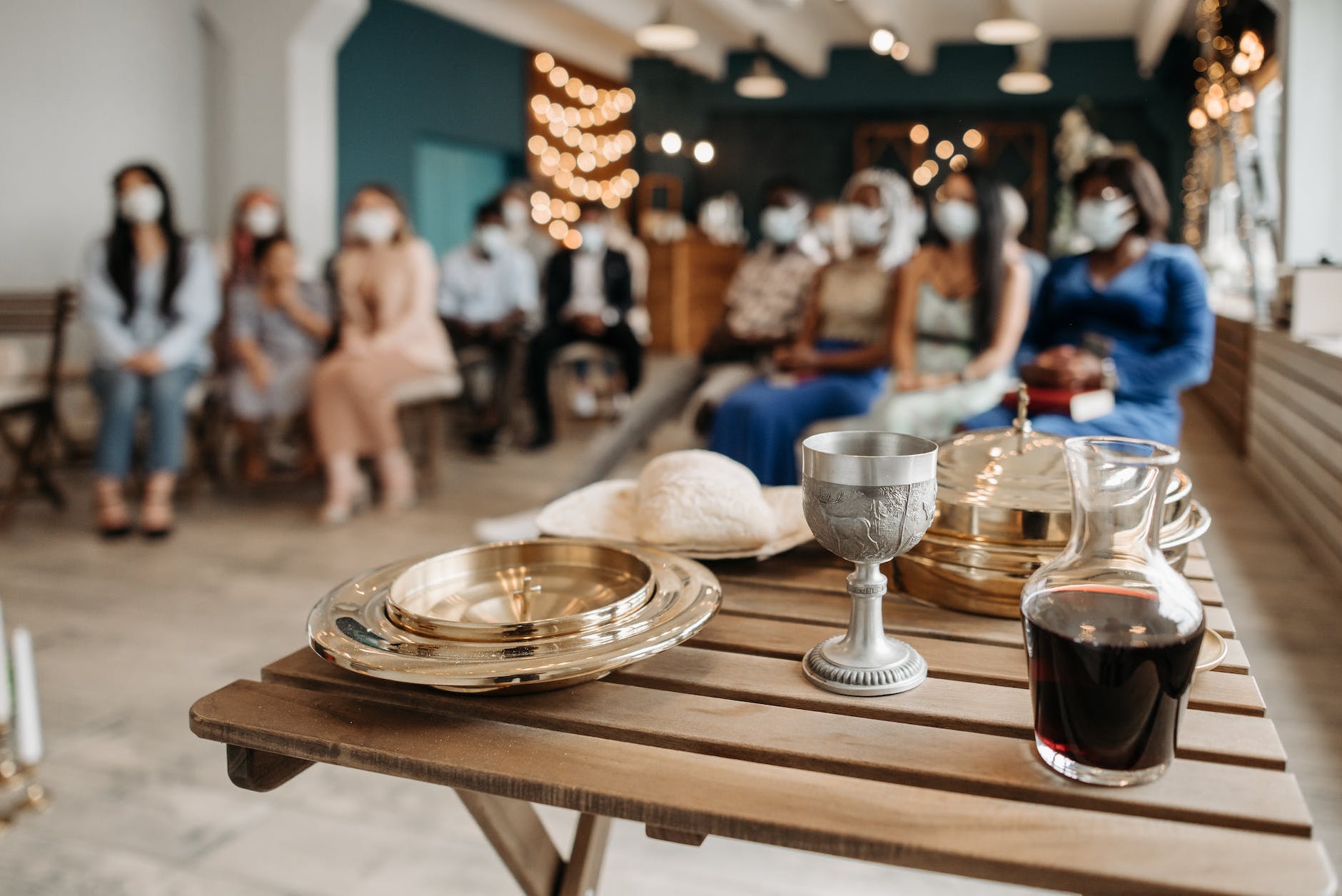communion trays and chalice beside a wine in bottle on brown wooden table